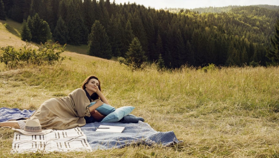 Agnieszka Maciąg leży na kocu na górskiej polanie. Opowiada o ciałopozytywności i o tym, jak nauczyć się kochać swoje ciało takim, jakie jest.