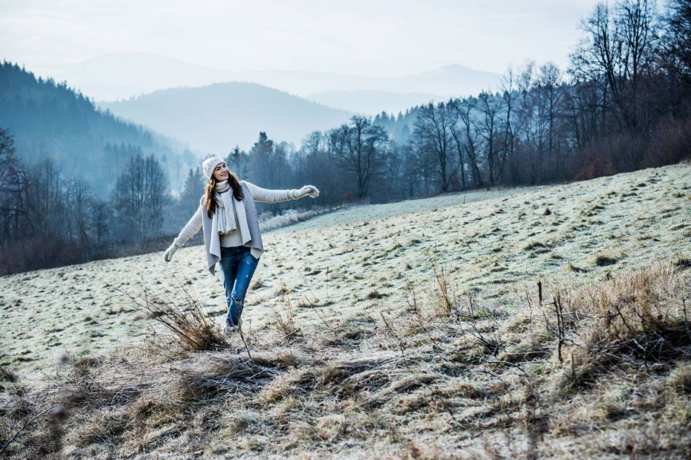Agnieszka Maciąg w ośnieżonych górach w białym swetrze, szaliku i białej czapce.