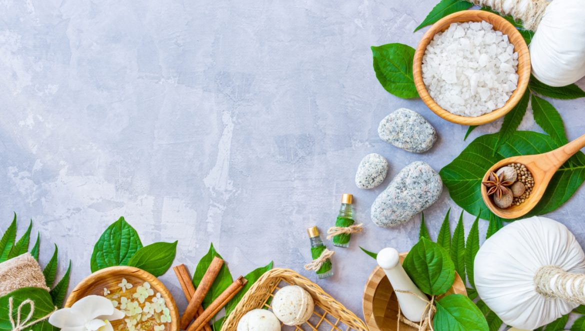 Ajurweda a Hashimoto - na czym polega leczenie ajurwedyjskie choroby autoimmunologicznej tarczycy? Widok z góry na przybory do masażu ajurwedyjskiego leżące na szarym blacie.