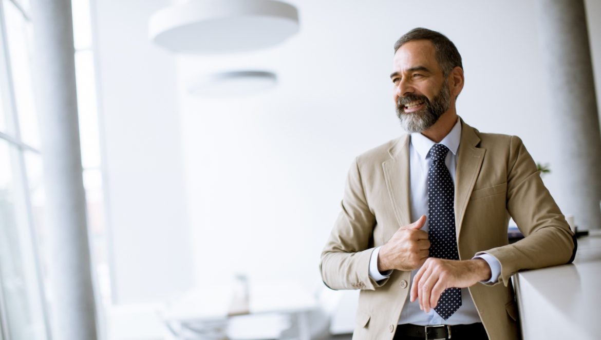 Andropauza - menopauza u mężczyzn - jakie są jej objawy, przyczyny i czy można ją leczyć? Elegancki starszy mężczyzna w garniturze w biurze.