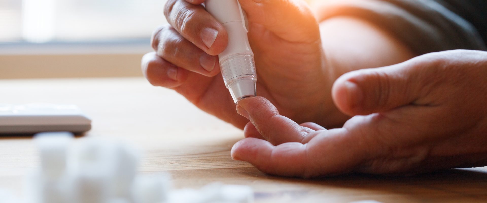 Hipoglikemia i hiperglikemia - jakie są objawy i jak pomóc? Kobieta mierzy sobie poziom glukozy we krwi za pomocą glukometru.