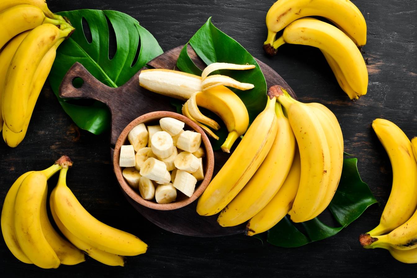 Banany dojrzałe na czarnym blacie. Jakie wartości odżywcze i właściwości prozdrowotne ma banan?
