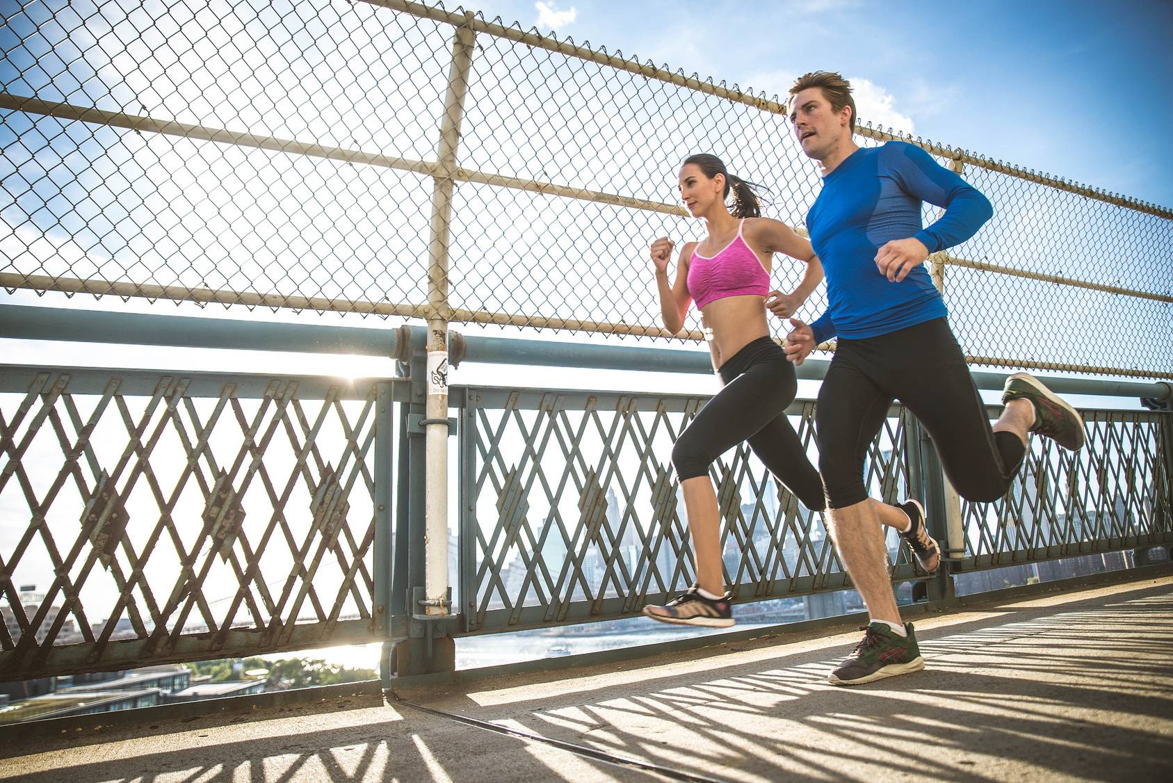 Biegacze nie muszą rezygnować z biegania, jeśli wynik rezonansu magnetycznego pokazuje zwyrodnienie kręgosłupa. Para biegaczy w strojach sportowych biegnie przez most.