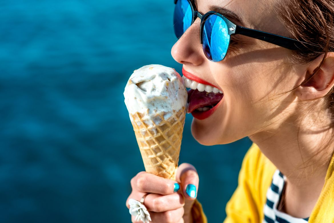 Jak poradzić sobie z bólem zęba na wakacjach? Kobieta je loda w wafelku.