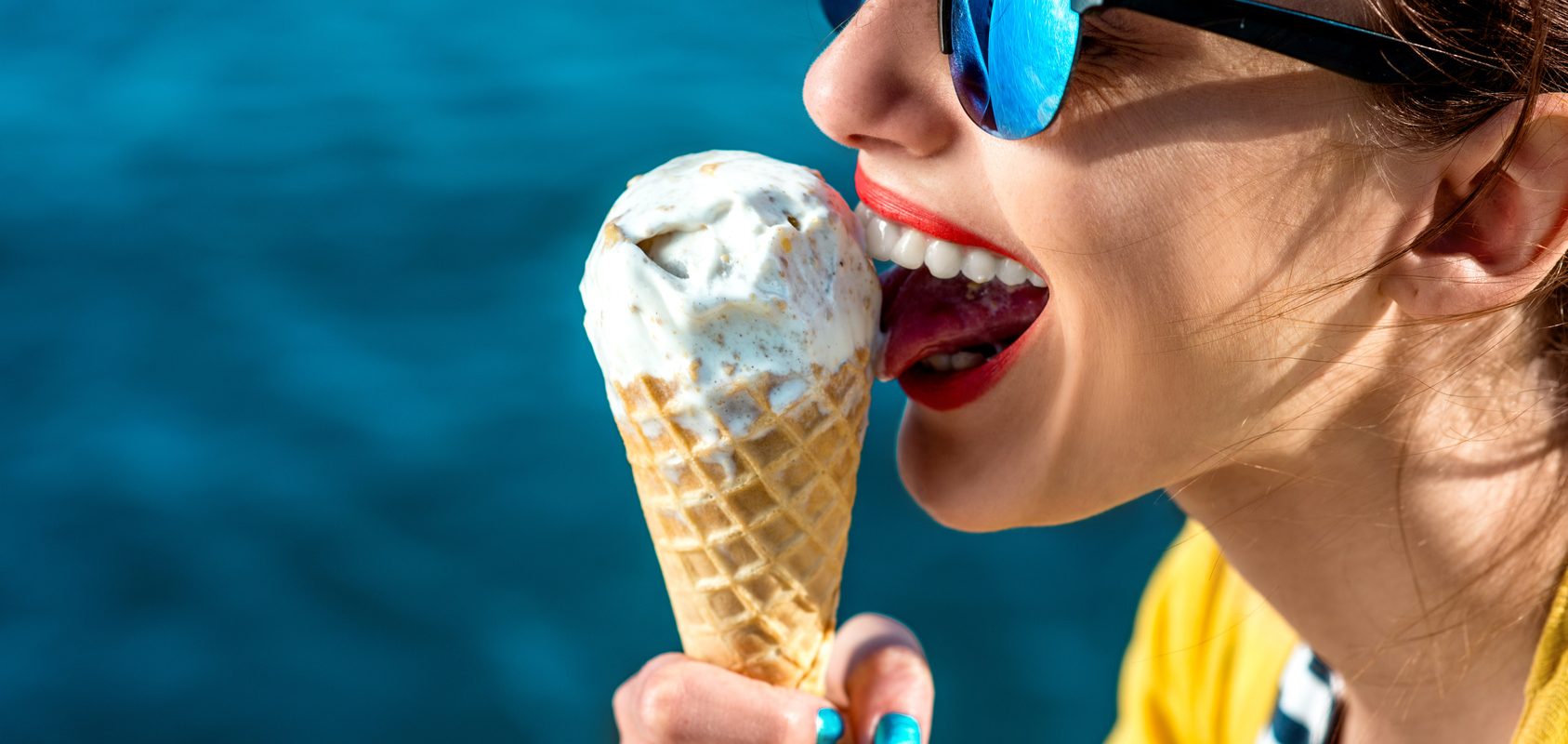 Jak poradzić sobie z bólem zęba na wakacjach? Kobieta je loda w wafelku.