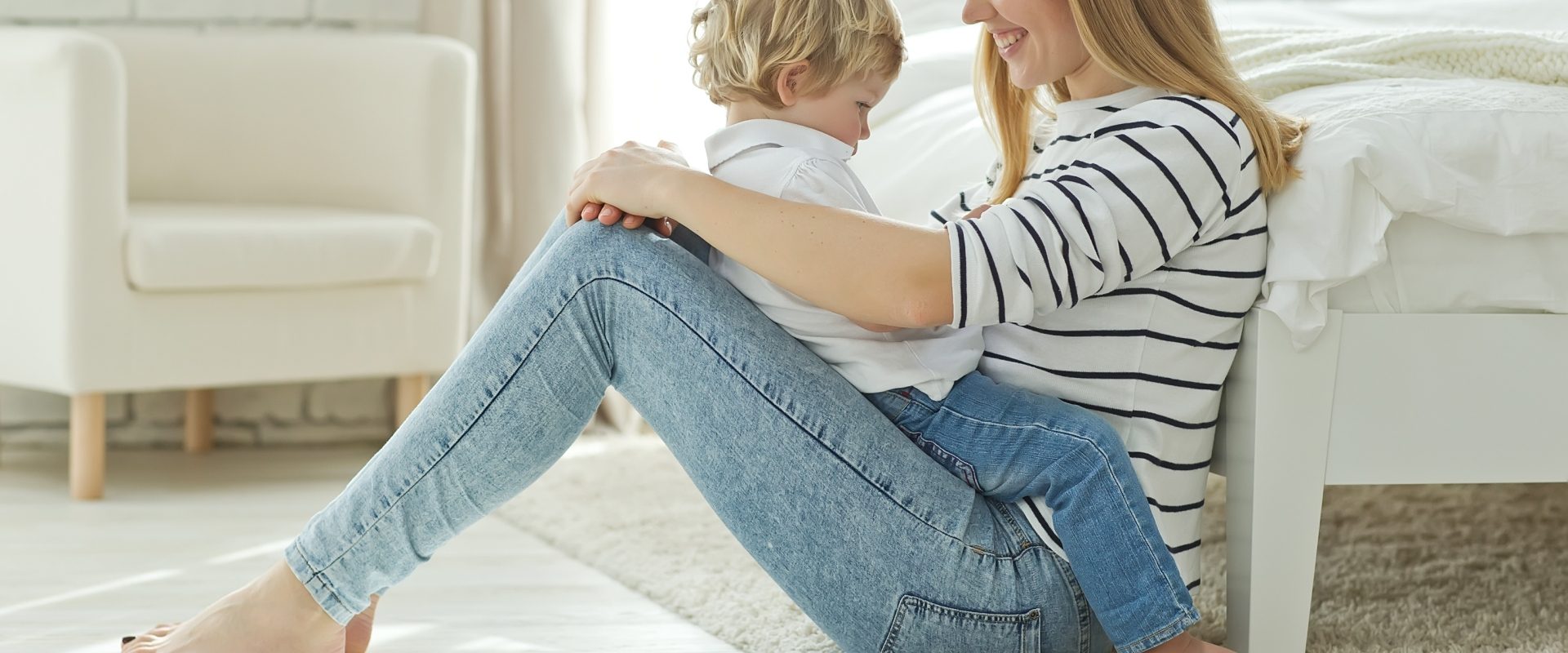 Jak radzić sobie z buntem dwulatka? Mama trzyma naburmuszonego synka na kolanach.