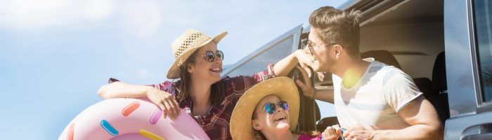 Jak radzić sobie z chorobą lokomocyjną? Jakie są najlepsze sposoby na chorobę lokomocyjną? Szczęśliwa rodzina na wakacjach nad wodą w letnich strojach z akcesoriami plażowymi.