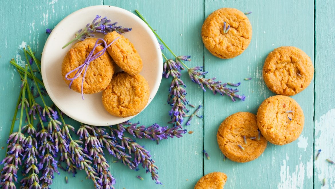 Ciasteczka lawendowe - przepis na ciastka z lawendą, lody lawendowe, muffinki, latte i sos do sałatki z lawedną. Ciasteczka z lawendą na talerzu na błękitnym drewnianym stole.