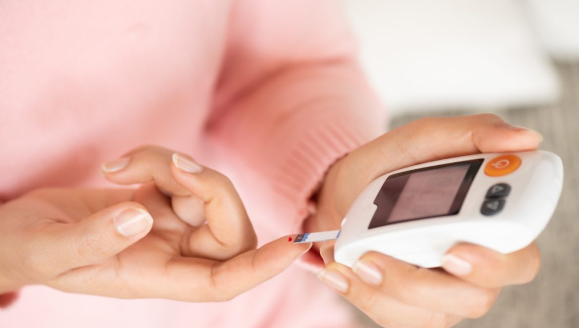 Cukrzyca typu 1 - objawy, przyczyny, leczenie. Jak radzić sobie i żyć z cukrzycą? Diabetyczka w różowym swetrze sprawdza poziom glukozy we krwi.