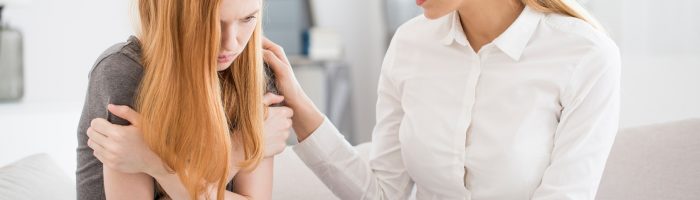 Jak pomóc nastolatkowi wyjść z depresji? Warsztaty forum przeciwko depresji - (Nie)widzialna nastoletnia depresja. Mama pociesza smutną nastoletnią córkę o rudych włosach.