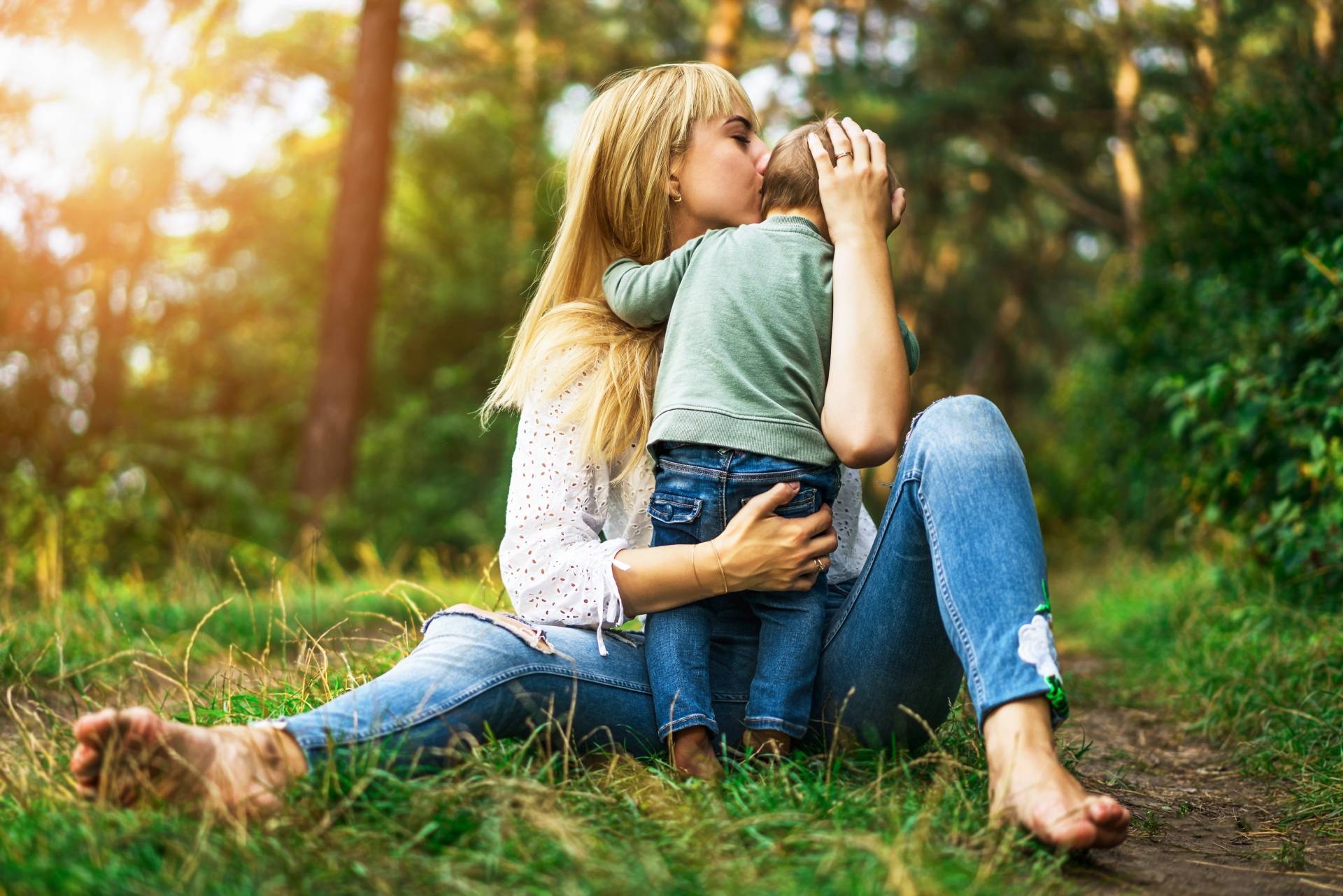 Stres u dzieci - jak się objawia? Mama przytula córeczkę na łonie natury.