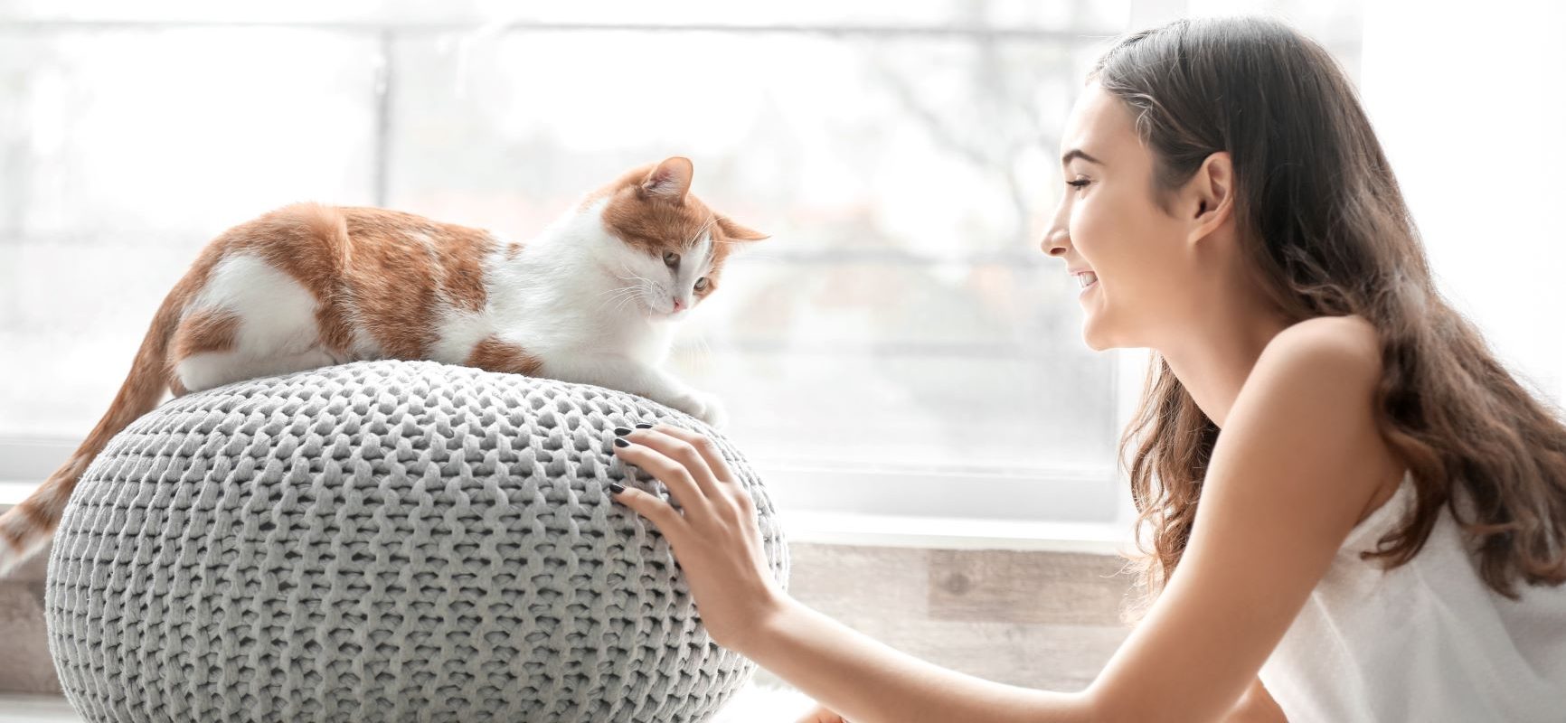 Felinoterapia - na czym polega terapia w towarzystwie kota? Młoda dziewczyna bawi się z kotem w domu.