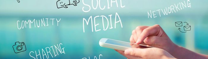 Syndrom FOMO (fear of missing out) 0 na czym polega i jak sobie z nim radzić? Kobiece dłonie piszą na smartfonie, a wokół lewitują napisy świadczące o uzależnieniu od Internetu.