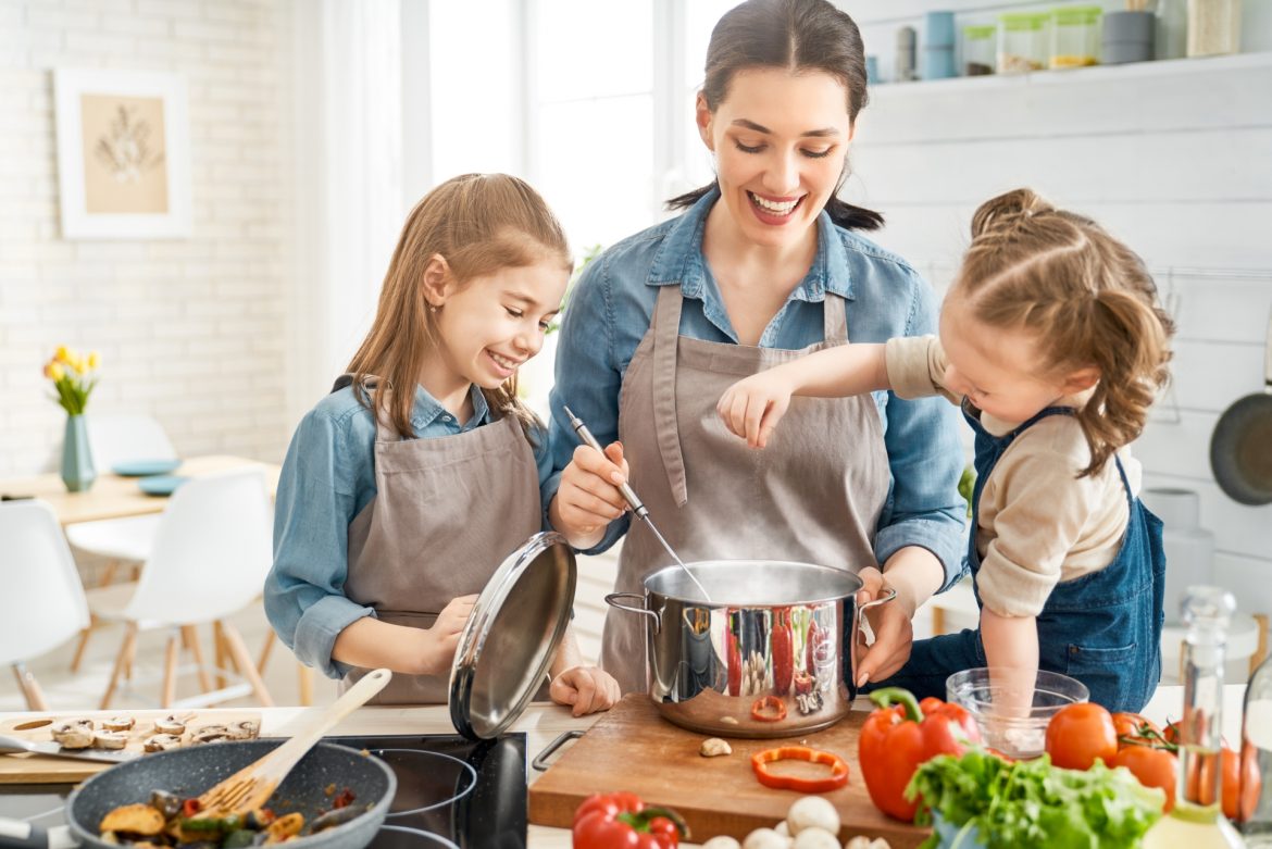 Garnki aluminiowe - zdrowe czy szkodliwe? Mama z dwójką dzieci gotują w kuchni w garnkach aluminiowych.