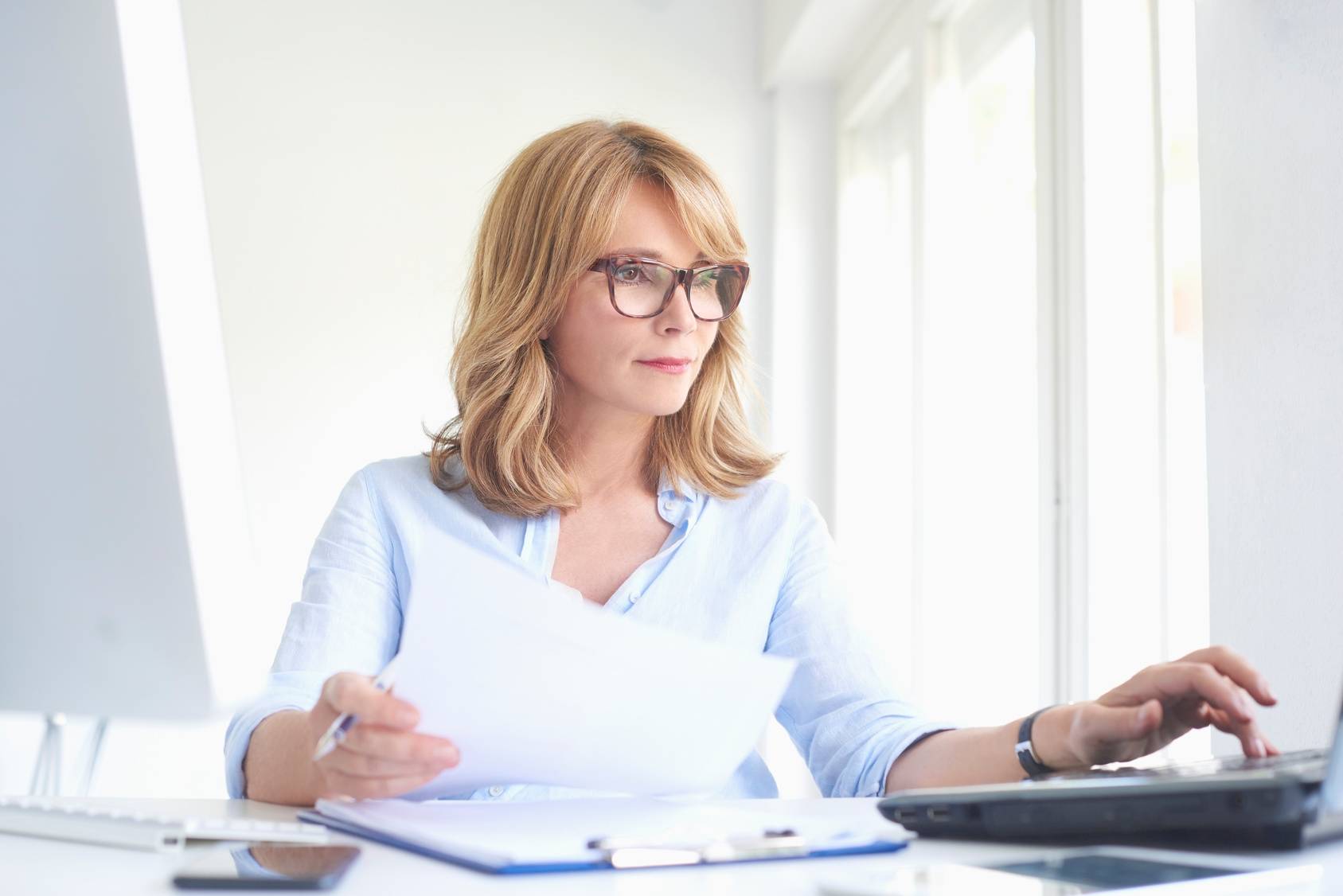 Jak dbać o wzrok po 40? Kobieta businesswoman w okularach z rogową oprawką siedzi przy komputerze.