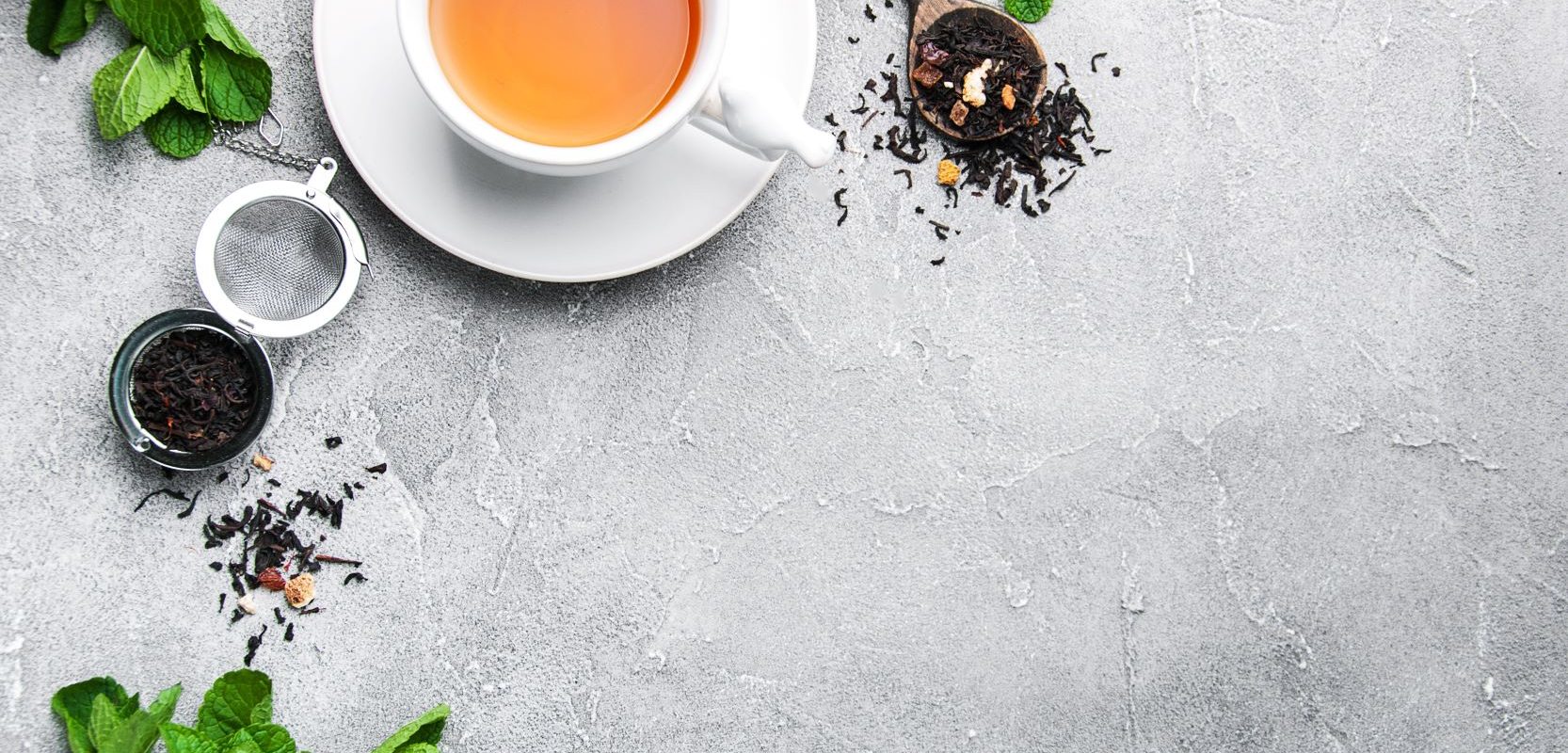 Co warto wiedzieć o herbacie? Herbata w białej filiżance na betonowym tle.
