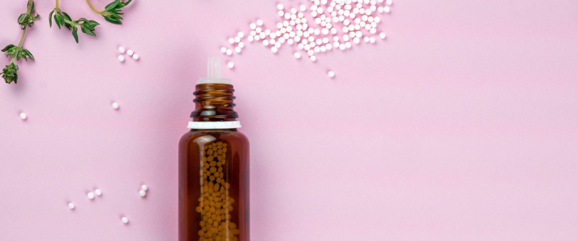 Cuprum metallicum - lek homeopatyczny na skurcze. Leżąca na płasko fiolka z wysypanymi lekami homeopatycznymi na fioletowym tle.