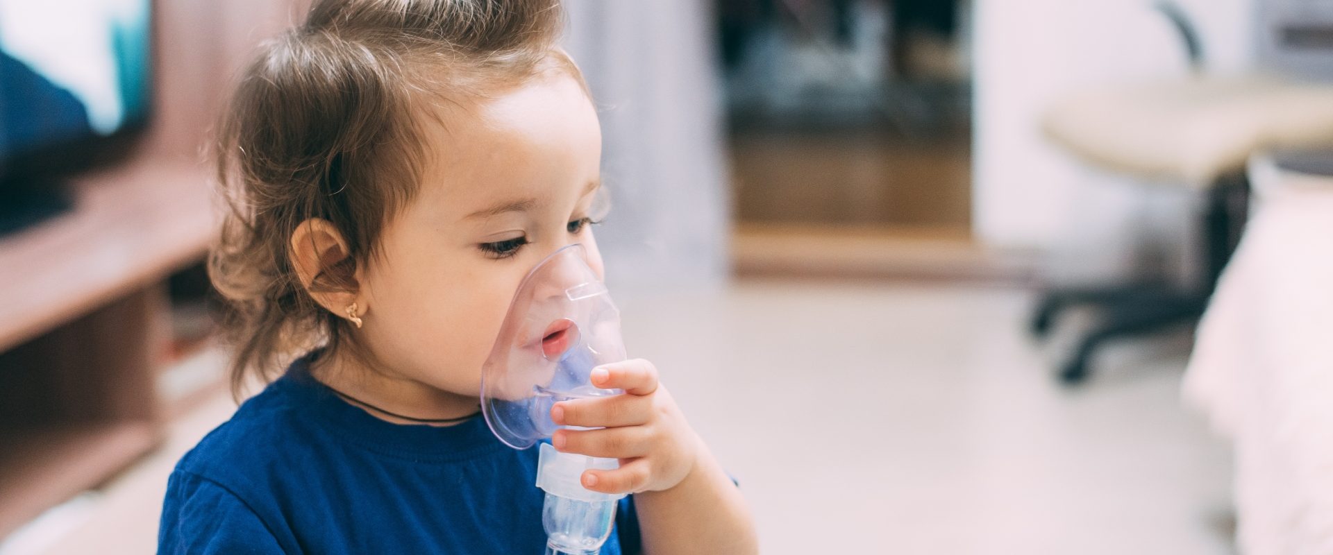 Nebulizacja i inhalacja dla dzieci - mała dziewczynka inhaluje się przy pomocy nebulizatora.
