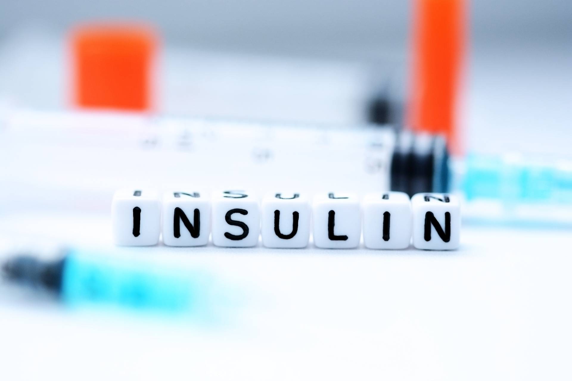 Insulina - jak hormon ten wpływa na procesy zachodzące w ludzkim organizmie? Czym jest insulina i dlaczego oporność na nią może prowadzić do chorób przewlekłych. Na blacie w laboratorium leżą strzykawki i ułożony z małych plastikowych klocków napis insulin.