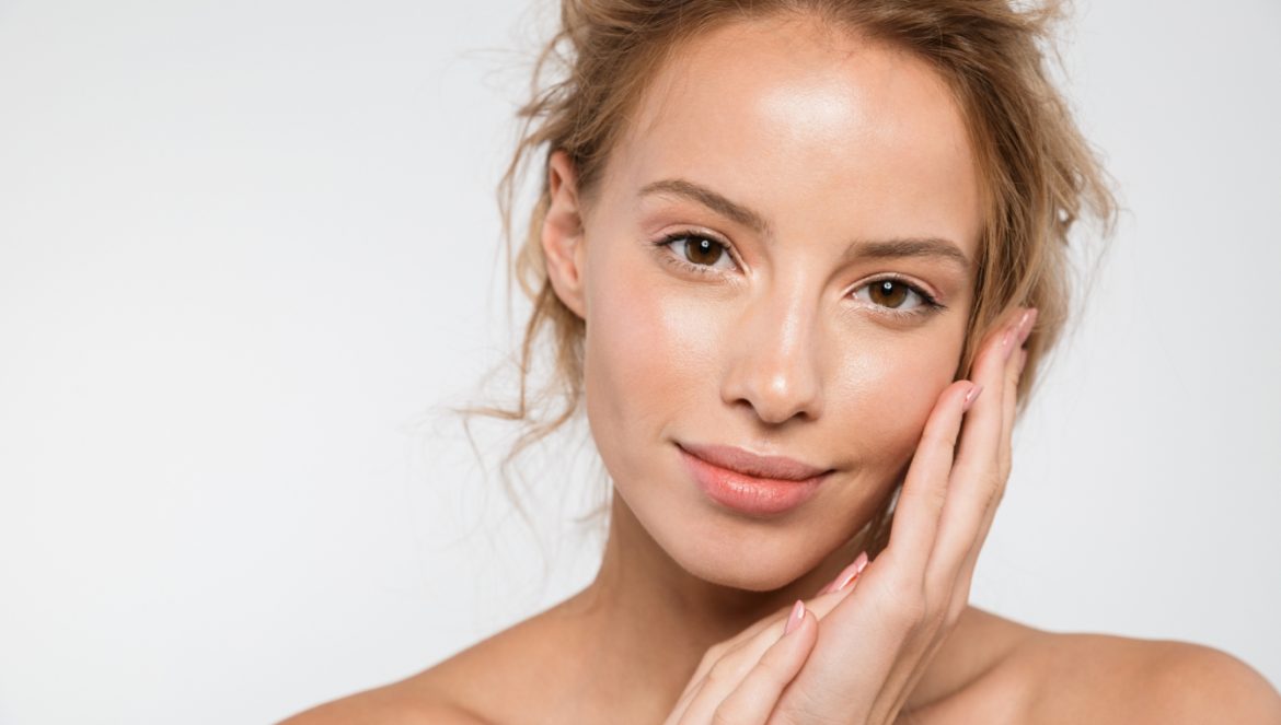 Izotretynoina w leczeniu trądziku - co warto wiedzieć o tej terapii? Młoda kobieta o dobrze nawilżonej i gładkiej twarzy pozuje na białym tle.