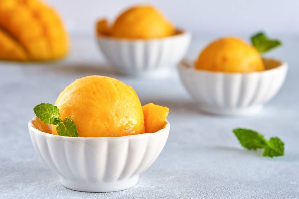 Jak zrobić sorbet? Przepisy na domowe lody owocowe Agnieszki Żelazko. Sorbet mango w białych miseczkach.