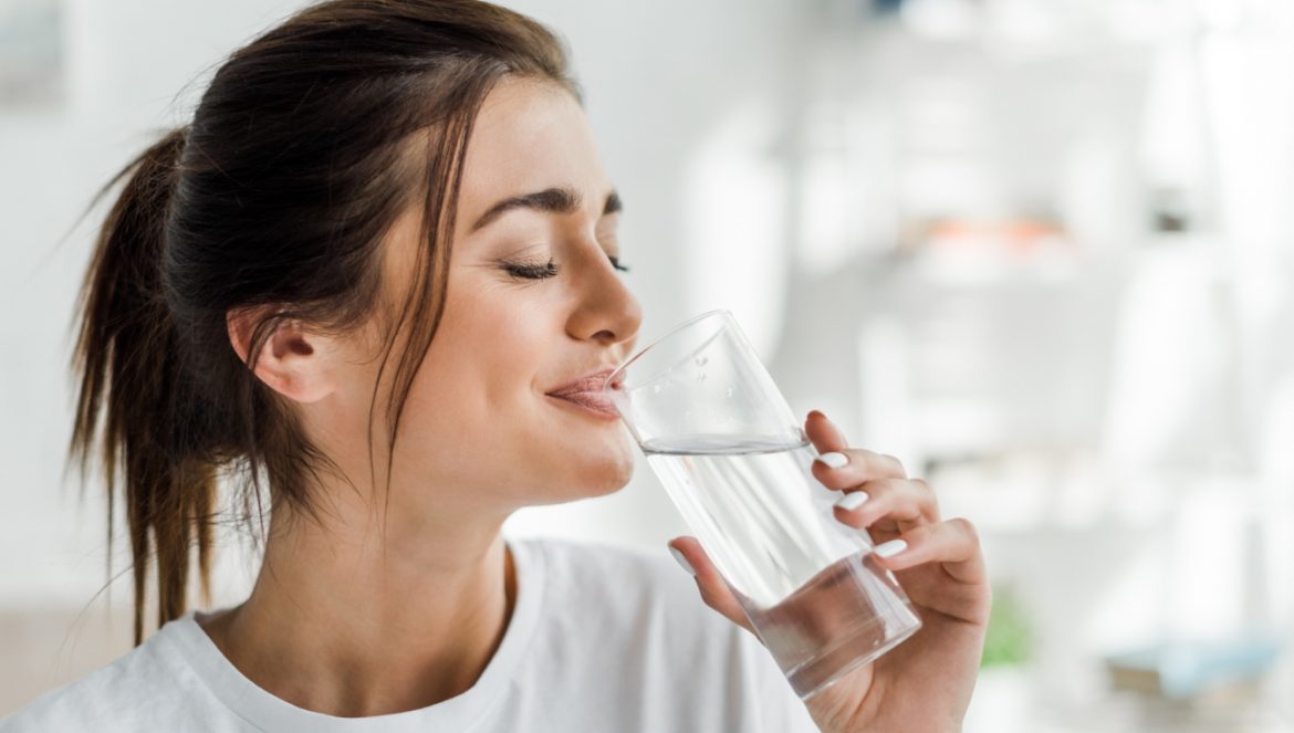 Japońska dieta wodna - na czym polega? Kobieta pije wodę ze szklanki.