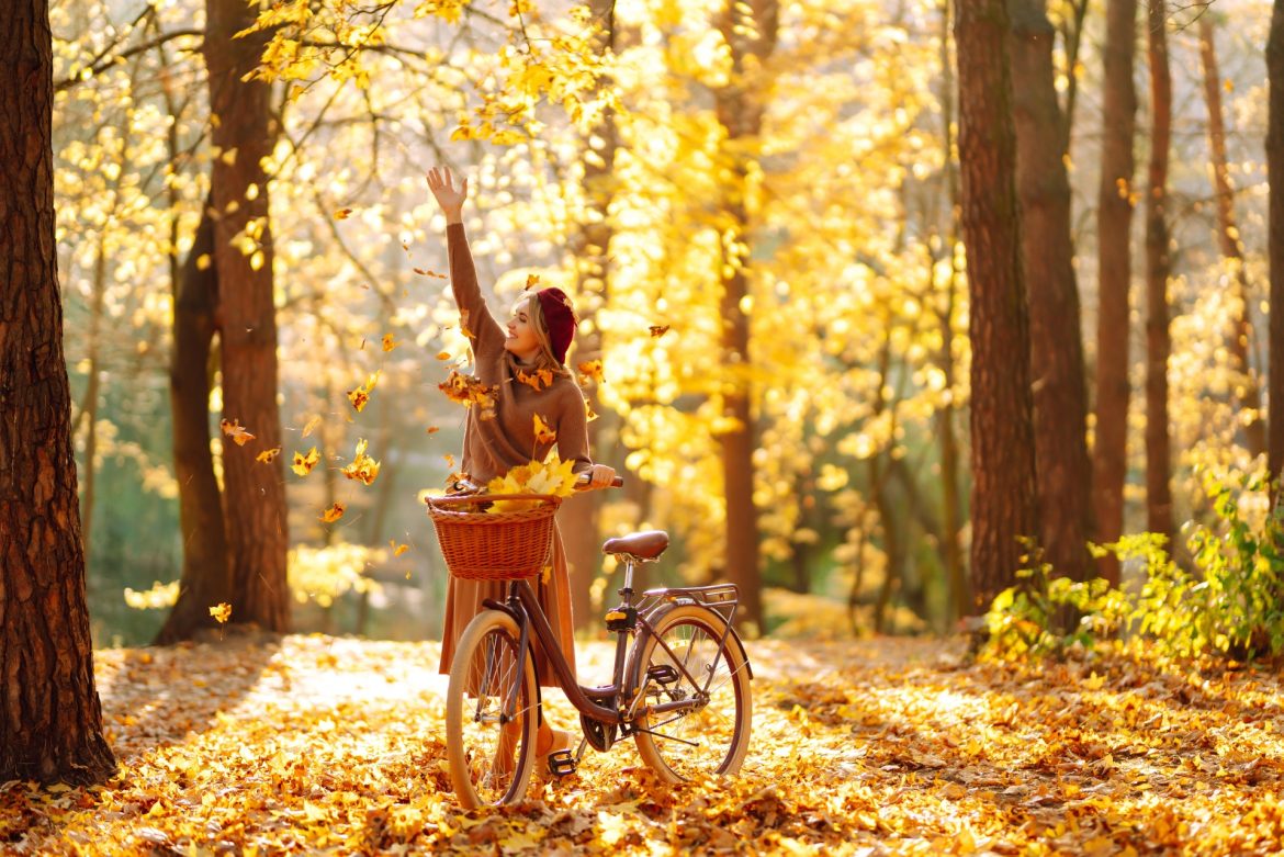 Czym jest odporność organizmu według medycyny chińskiej? Młoda kobieta zbiera jesienne liście podczas przejażdżki rowerem po lesie.