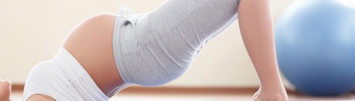 Nie możesz zajść w ciążę? Zacznij praktykować jogę! Kobieta w ciąży praktykuje jogę na macie na sali gimnastycznej.