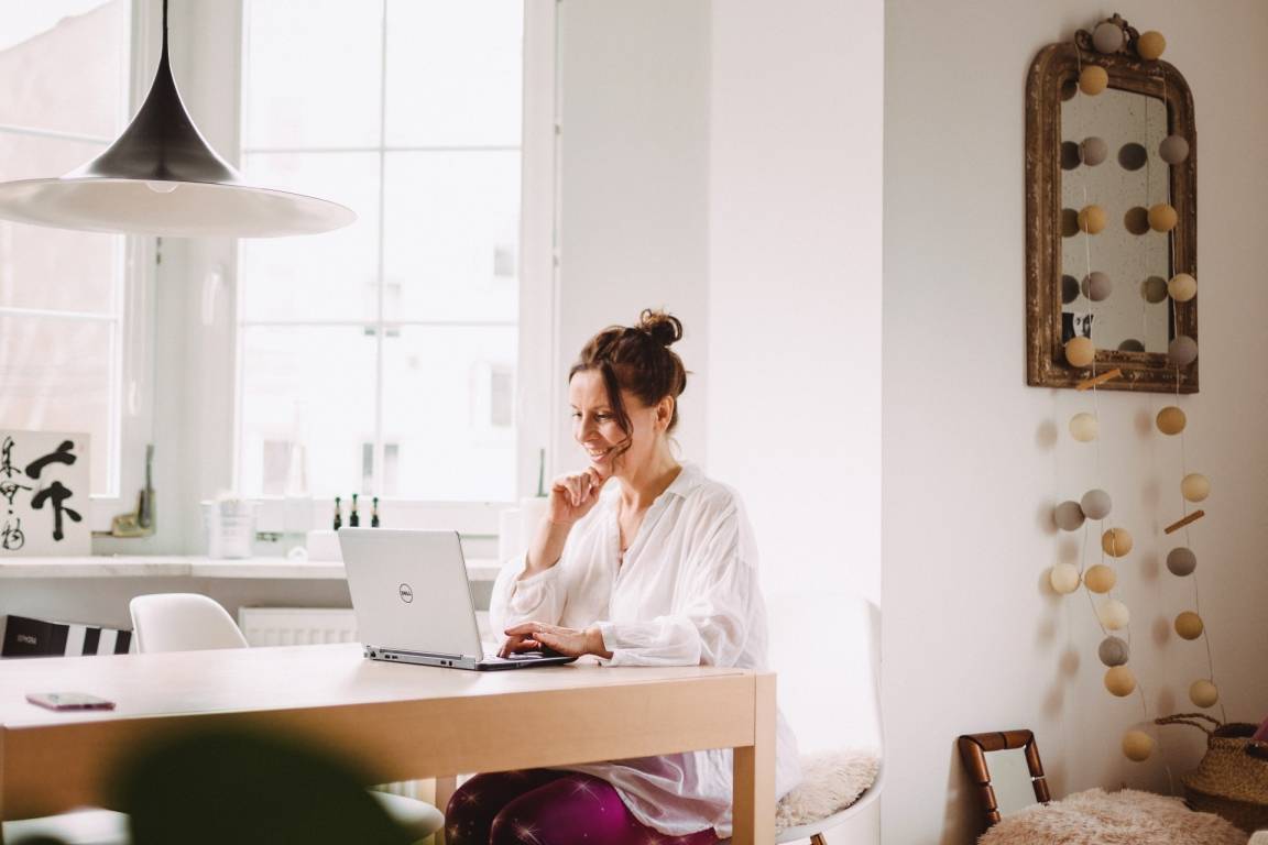 Kasia Bem, joginka, siedzi przy laptopie w domu.