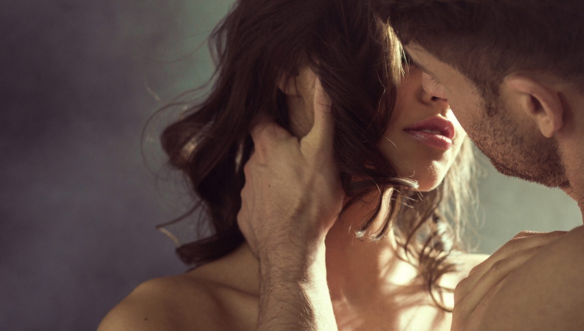 Wstyd, hańba i poświęcenie – kobieca rozkosz przez epoki. O kobiecej seksualności. Mężczyzna całuje kobietę dotykając ręką jej włosów.