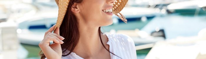 5 leków homeopatycznych na kobiece emocje. Atrakcyjna kobieta w kapeluszu słomkowym i białej koszuli stoi na molo na wakacjach.