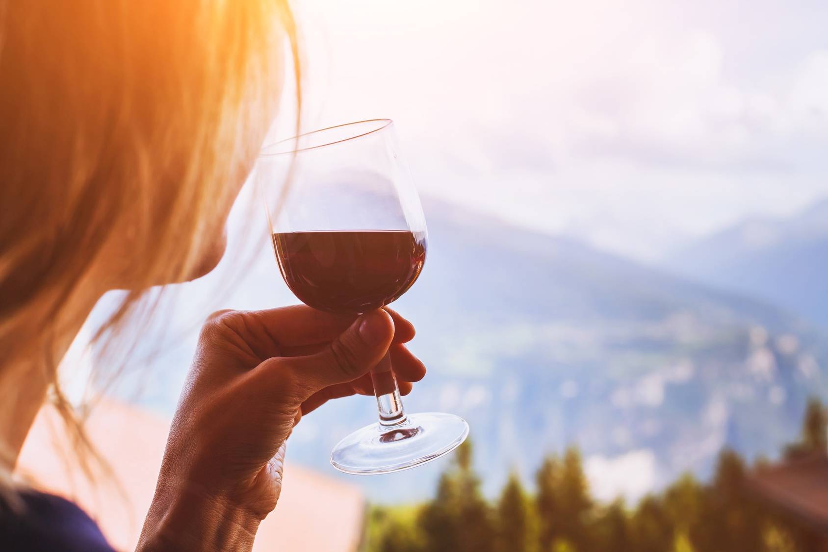 Sirtuiny - eliksir młodości, białka odpowiedzialne za długowieczność i szczupłą sylwetkę. Kobieta pije czerwone wino z kieliszka.