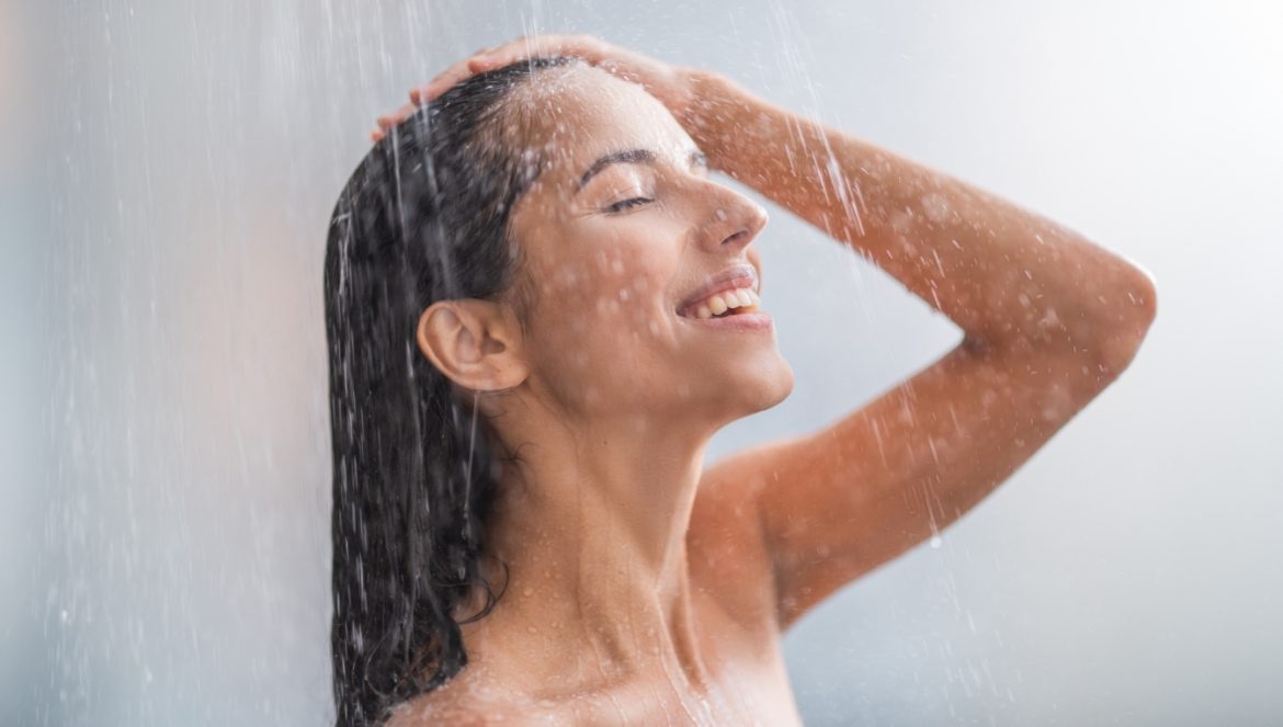 Prysznic latem dla zdrowia i urody. Kobieta bierze kąpiel pod prysznicem w gorący letni dzień.