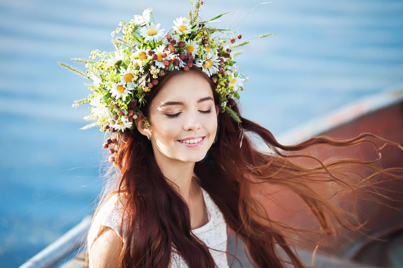 Czym jest alergia? Młoda ciemnowłosa dziewczyna w pięknym, bogato zdobionym wianku z kwiatów siedzi na łodzi i się uśmiecha. 