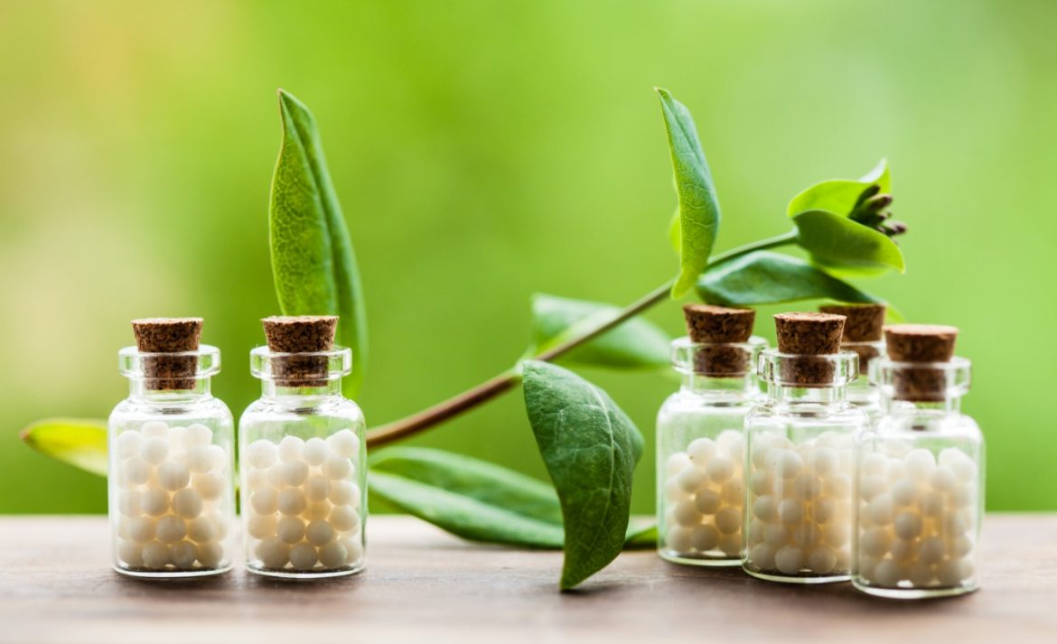 Magnesia carbonica - lek homeopatyczny dla dzieci i dorosłych. Fiolki z granulkami homeopatycznymi na zielonym tle.