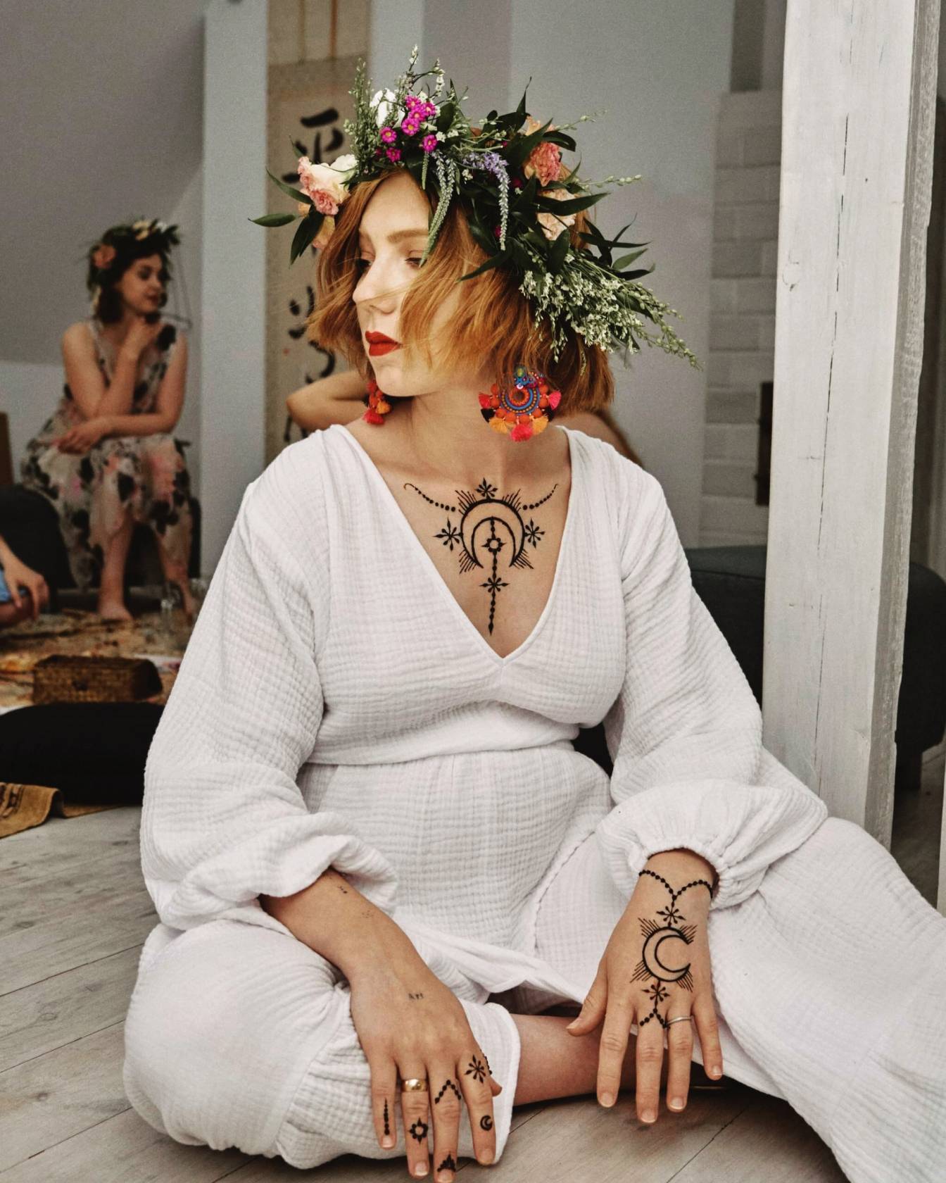 Marianna Gierszewska w białym lnianym kostiumie, wianku na głowie i tatuażach henny.