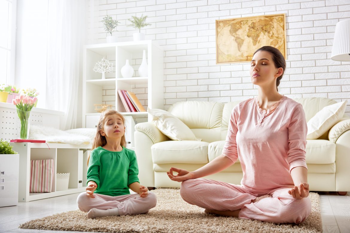 Medytacja dla dzieci - ćwiczenia i zabawy relaksacyjne dla maluchów i starszaków. Mama i córka medytują w domu w salonie.