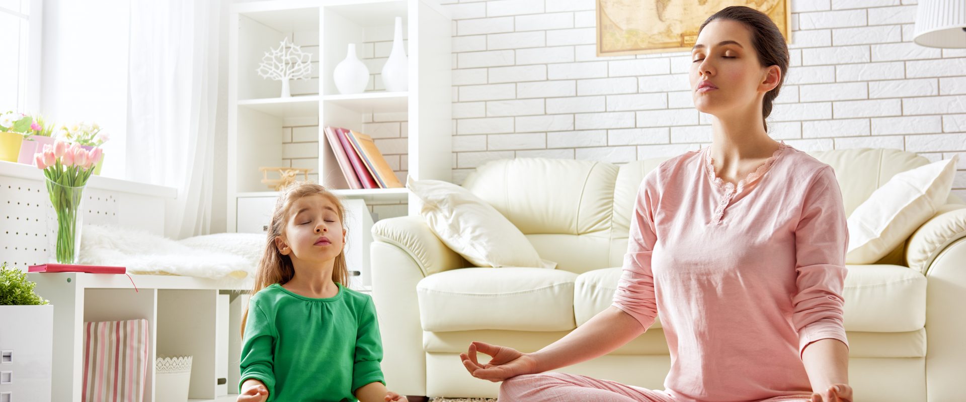 Medytacja dla dzieci - ćwiczenia i zabawy relaksacyjne dla maluchów i starszaków. Mama i córka medytują w domu w salonie.