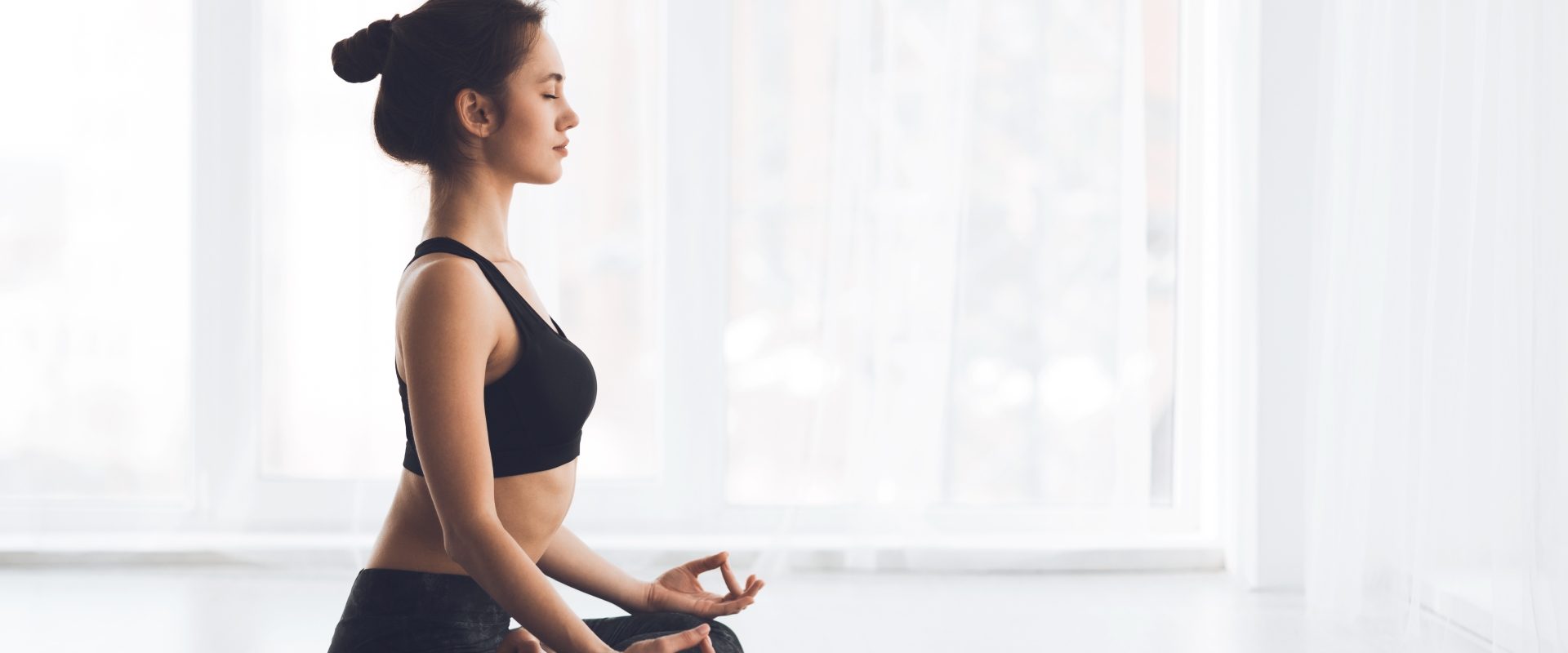 Proste ćwiczenia na rozładowanie stresu. Kobieta w czarnym stroju do jogi medytuje na macie.