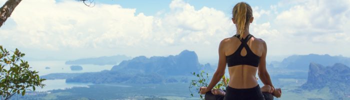 Mindfulness - trening uważności. Kobieta medytuje wśród przyrody w górach.