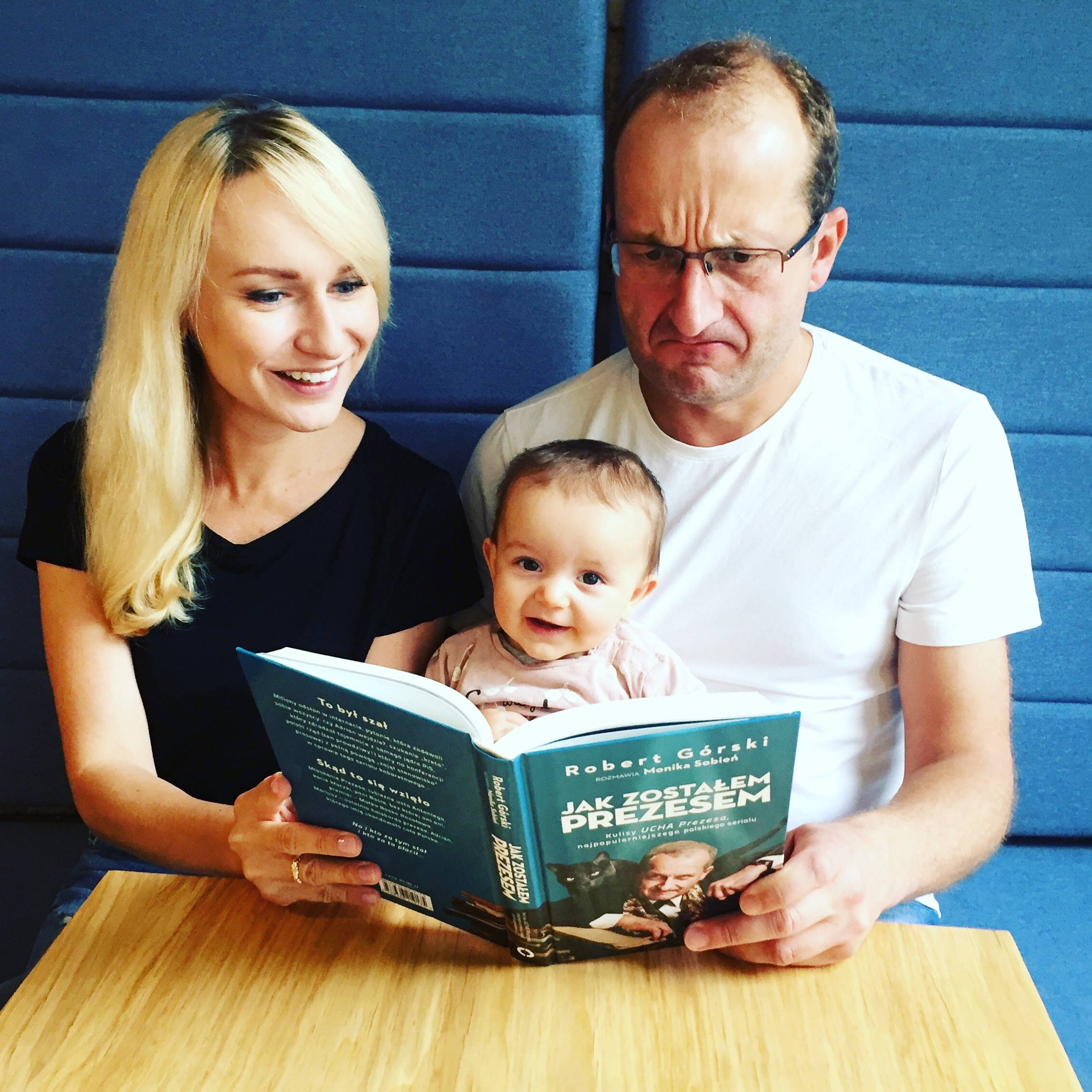 Monika Sobień-Górska i Robert Górski z córeczką czytają książkę.