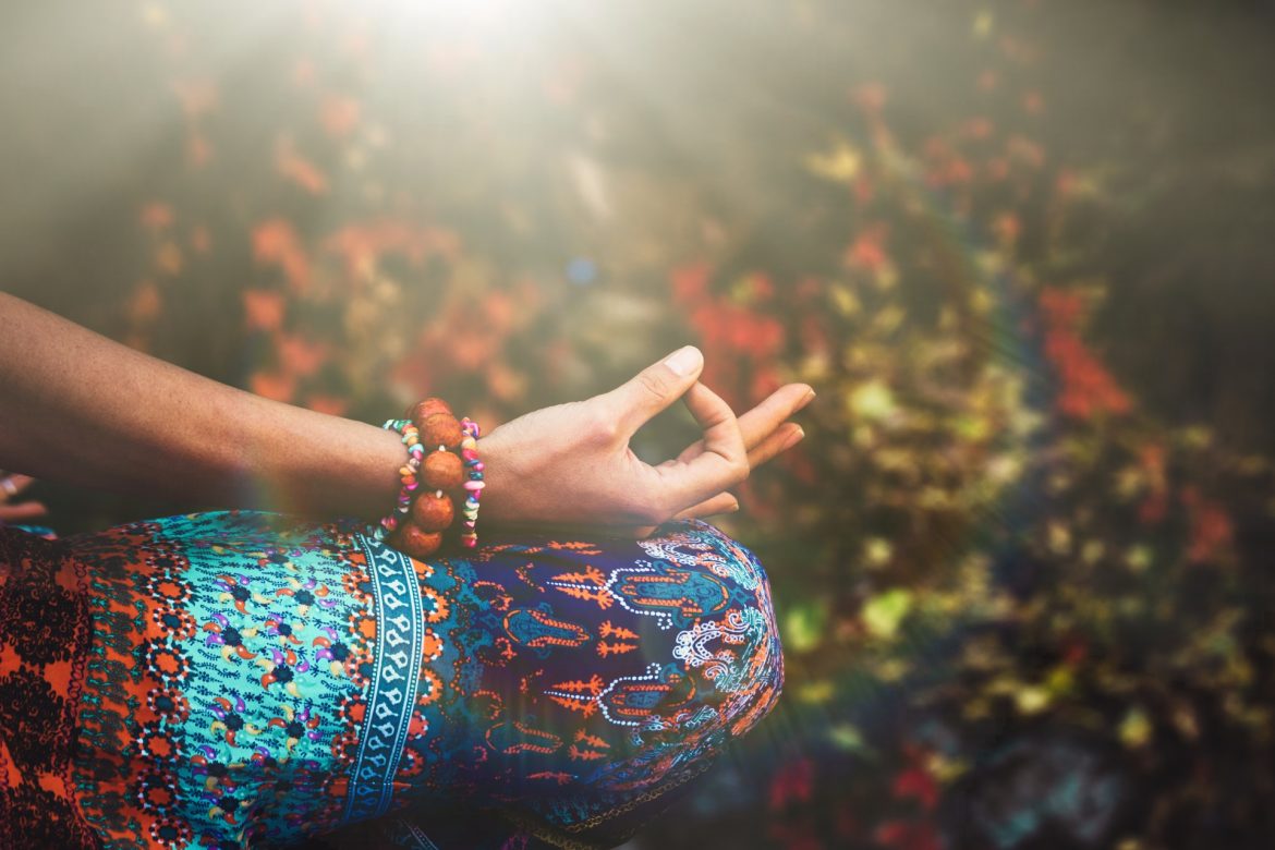 Mudry - gesty dłoni w ajurwedzie. Kobieta ćwiczy jogę lub medytuje układając dłonie w mudry.