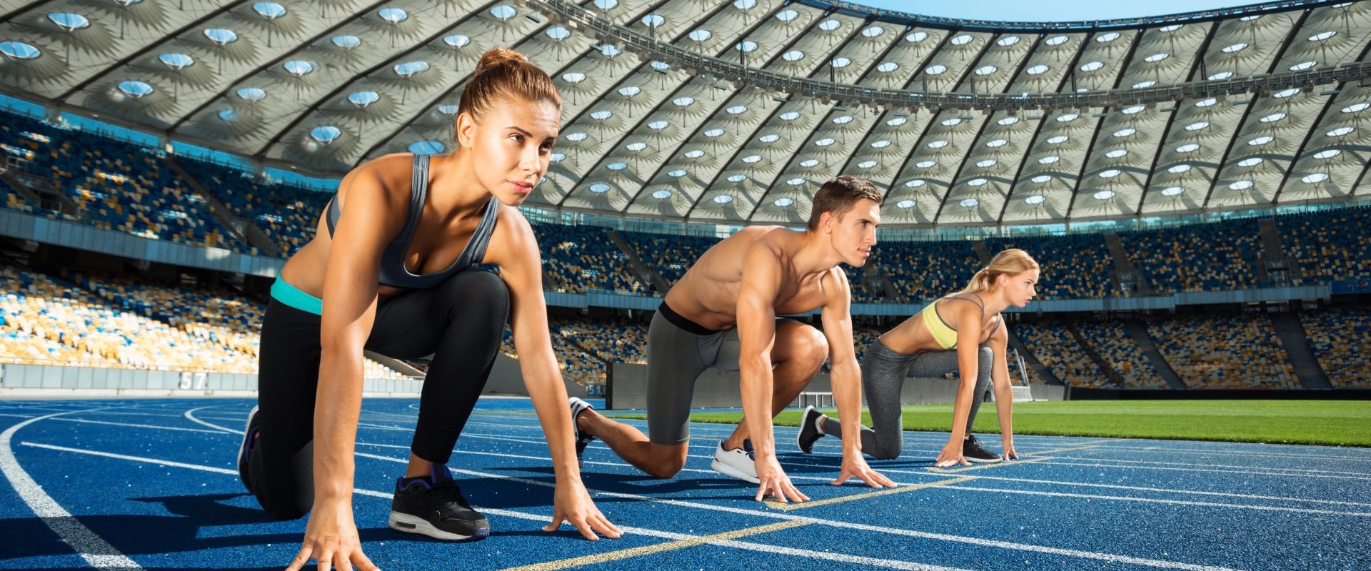 Myśl jak sportowiec, a zaczniesz wygrywać. Czego nas uczy psychologia sportu? Zawodnicy w przysiadzie na starcie na bieżni czekają na sygnał do biegu.