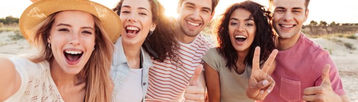 W jaki sposób bakterie w jelitach wpływają na nasz nastrój? Jak flora bakteryjna jelit oddziałuje na nasz mózg? Grupa uśmiechniętych przyjaciół pozuje do zdjęcia na plaży.