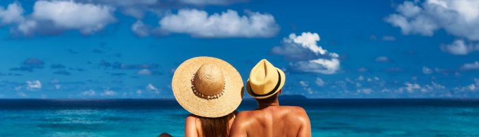 Jak przygotować skórę do opalania? Co jeść i czym smarować skórę? Para siedzi na plaży na tropikalnej wyspie na Seszelach.