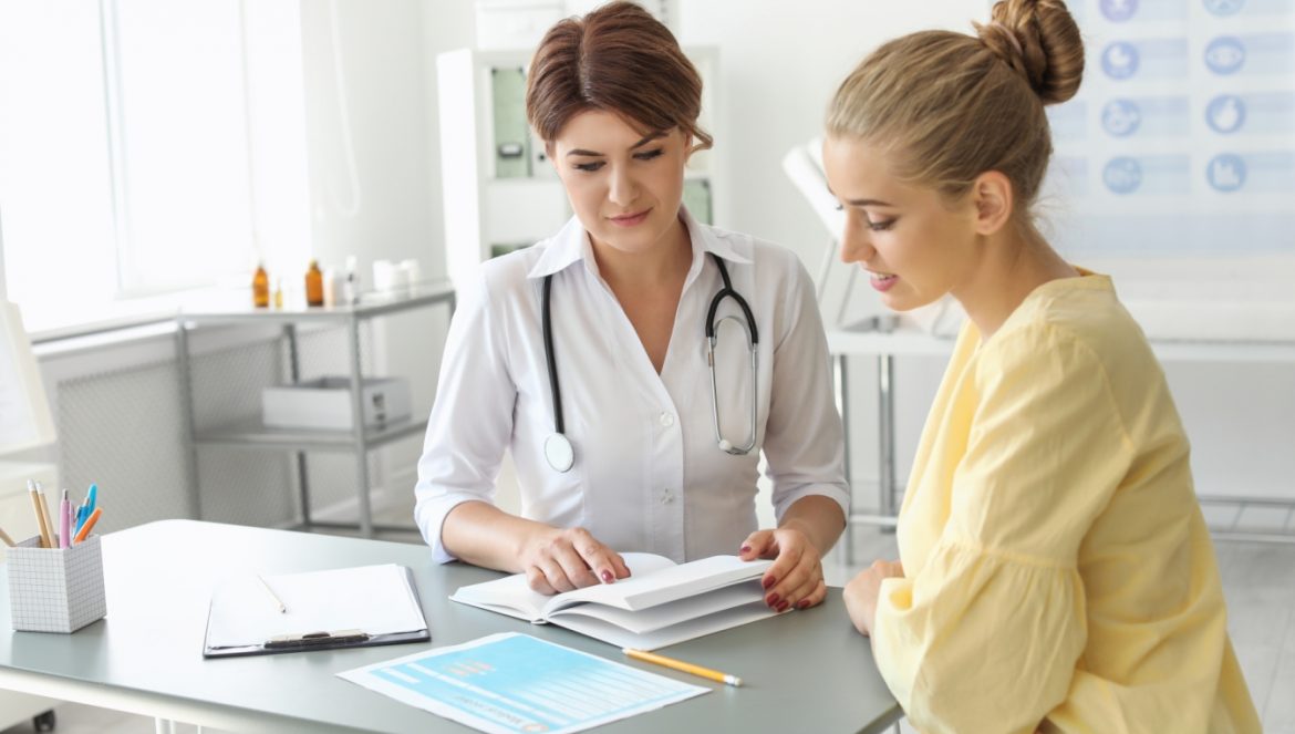 Niskie ciśnienie krwi - jak sobie z tym poradzić? Młoda kobieta na wizycie w gabinecie lekarskim słucha diagnozy od pani doktor.