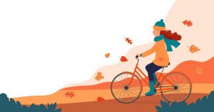 10 produktów wzmacniających odporność i zwalczających wirusy. Ilustracja w jesiennych barwach: kobieta jedzie na rowerze w swetrze, czapce i szaliku jesienią.
