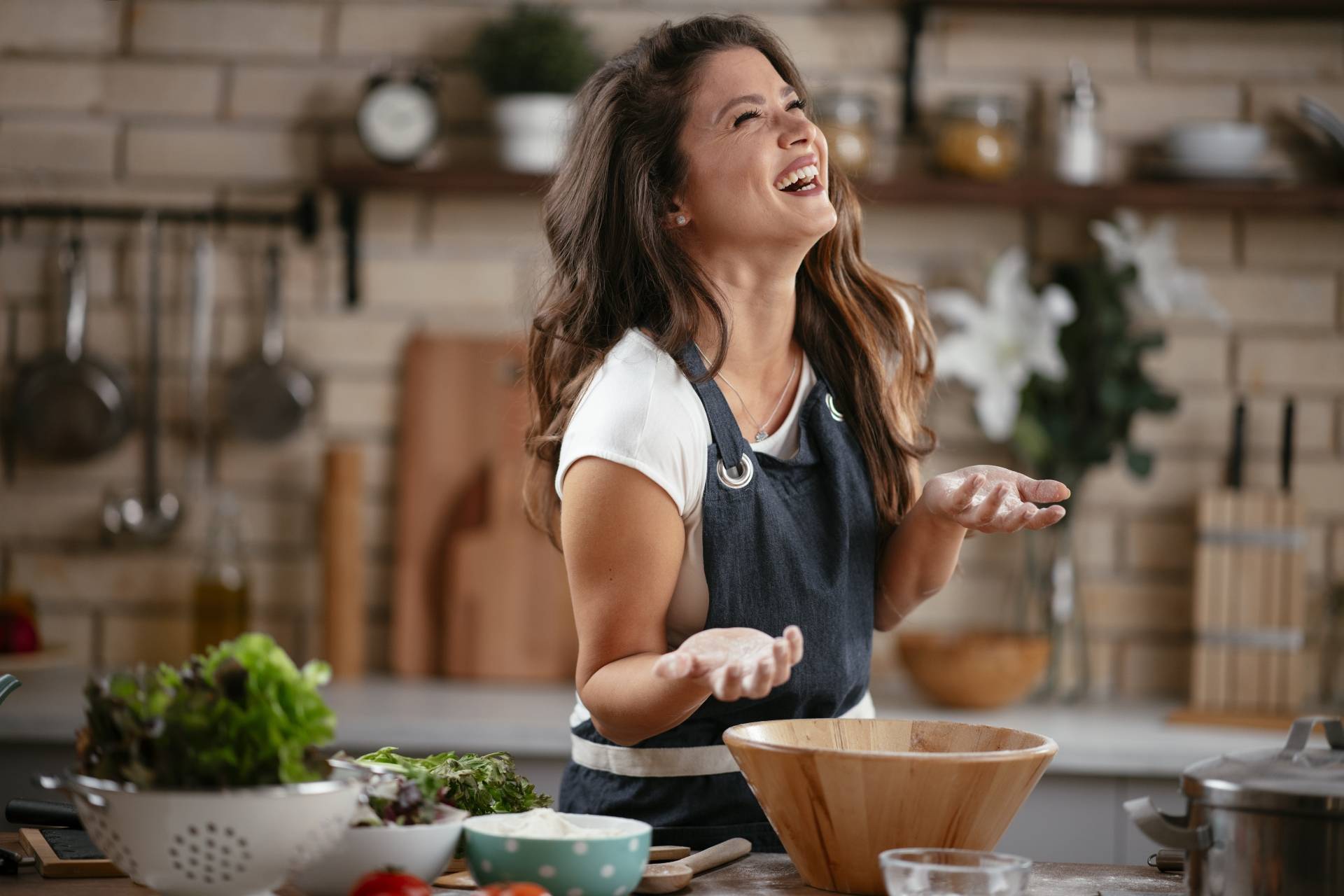 Jak poprawić odporność według medycyny chińskiej? W jaki sposób rozgrzewające potrawy wspierają układ odpornościowy? Uśmiechnięta kobieta gotuje w kuchni w domu.