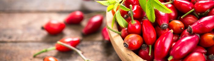 Owoce dzikiej róży w drewnianej misce.