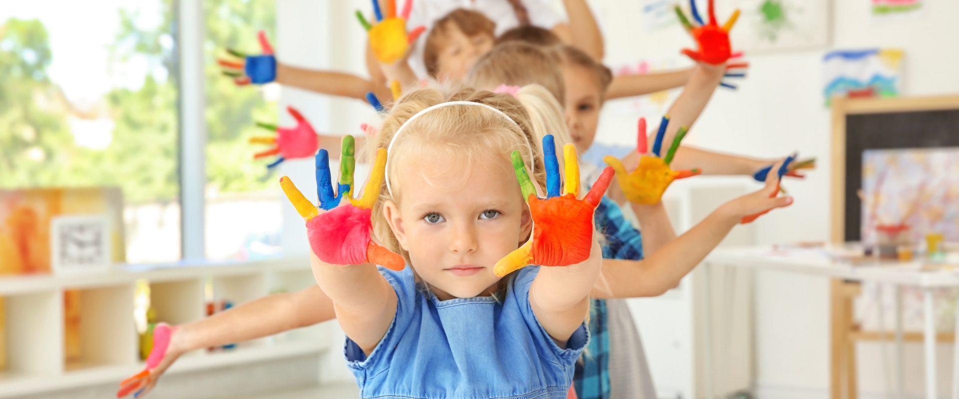 Owsiki u dzieci. Przedszkolaki i przedszkolanka pozują do zdjęcia z dłońmi pomalowanymi farbą.